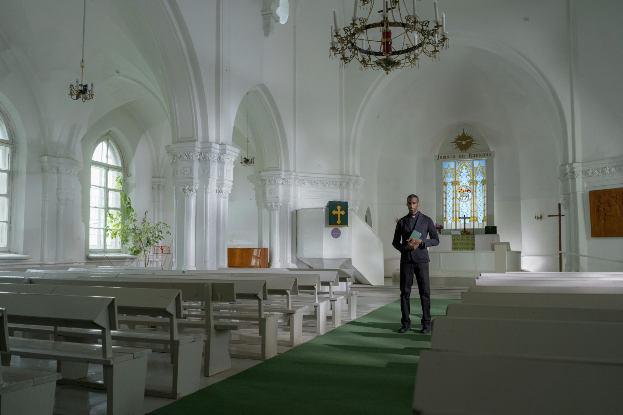 Modern church interior with a cleric standing by the altar, illuminated by natural light.